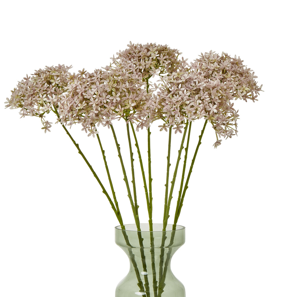 Several lilac-grey botanical sprays arranged in a translucent green vase, with clustered florets spread across the top and the vase partly cropped.