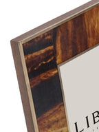 Close-up of the frame's upper corner, showing amber and black resin bands edged with slim brass detailing.