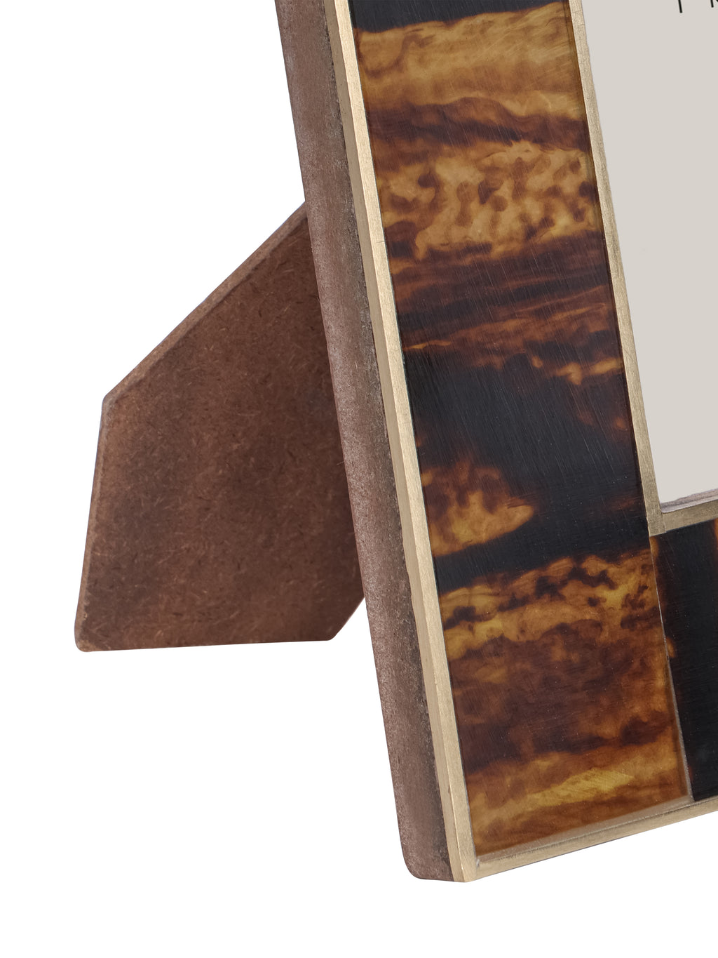 Close-up of the frame's lower side with mottled amber and dark brown bands, brass trim and the rear support visible.