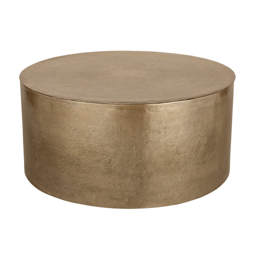 Arcade champagne-gold drum coffee table viewed at an angle, showing the round top and textured curved body.