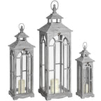 Three pale grey Archwindow lanterns in graduated sizes, with pitched roofs, loop tops and cream pillar candles shown inside.