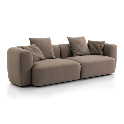 Angled front view showing the sofa’s deep seats, curved left arm and low back in truffle velvet.