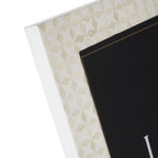 Close-up of the frame's upper corner, showing pale angular bone-inlay pieces across the white border.