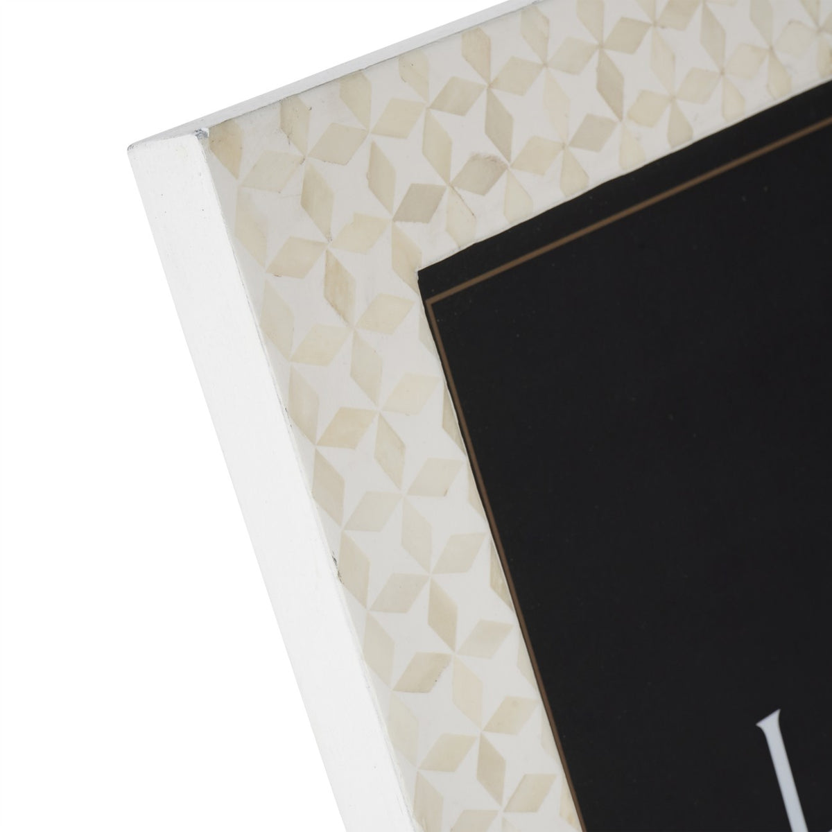 Close-up of the frame's upper corner, showing pale angular bone-inlay pieces across the white border.