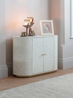 White bone-inlay photo frame holding a flower image on a patterned cabinet beside two lit decorative candleholders with elephant figures.