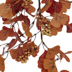 Close-up of fan-shaped orange and burgundy leaves with dark vein details and mottled tan berries on brown branches.