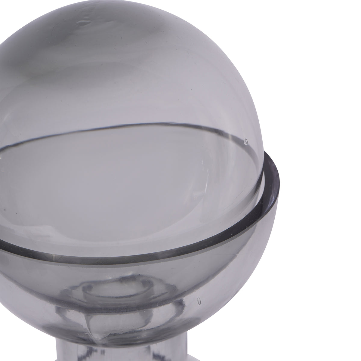 Close-up of the smoky glass ball resting inside the vase rim, with reflections and small bubbles visible in the glass.