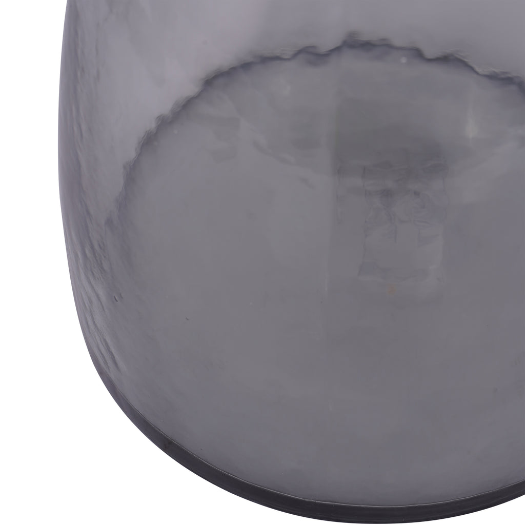 Close-up of the vase's curved grey glass body and dark base edge, with the base visible through the tinted surface.