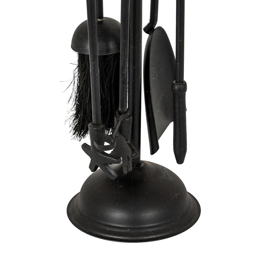 Detail of the hanging black fireside tool ends, dark brush bristles and shovel blade above the domed base.