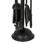 Detail of the hanging black fireside tool ends, dark brush bristles and shovel blade above the domed base.