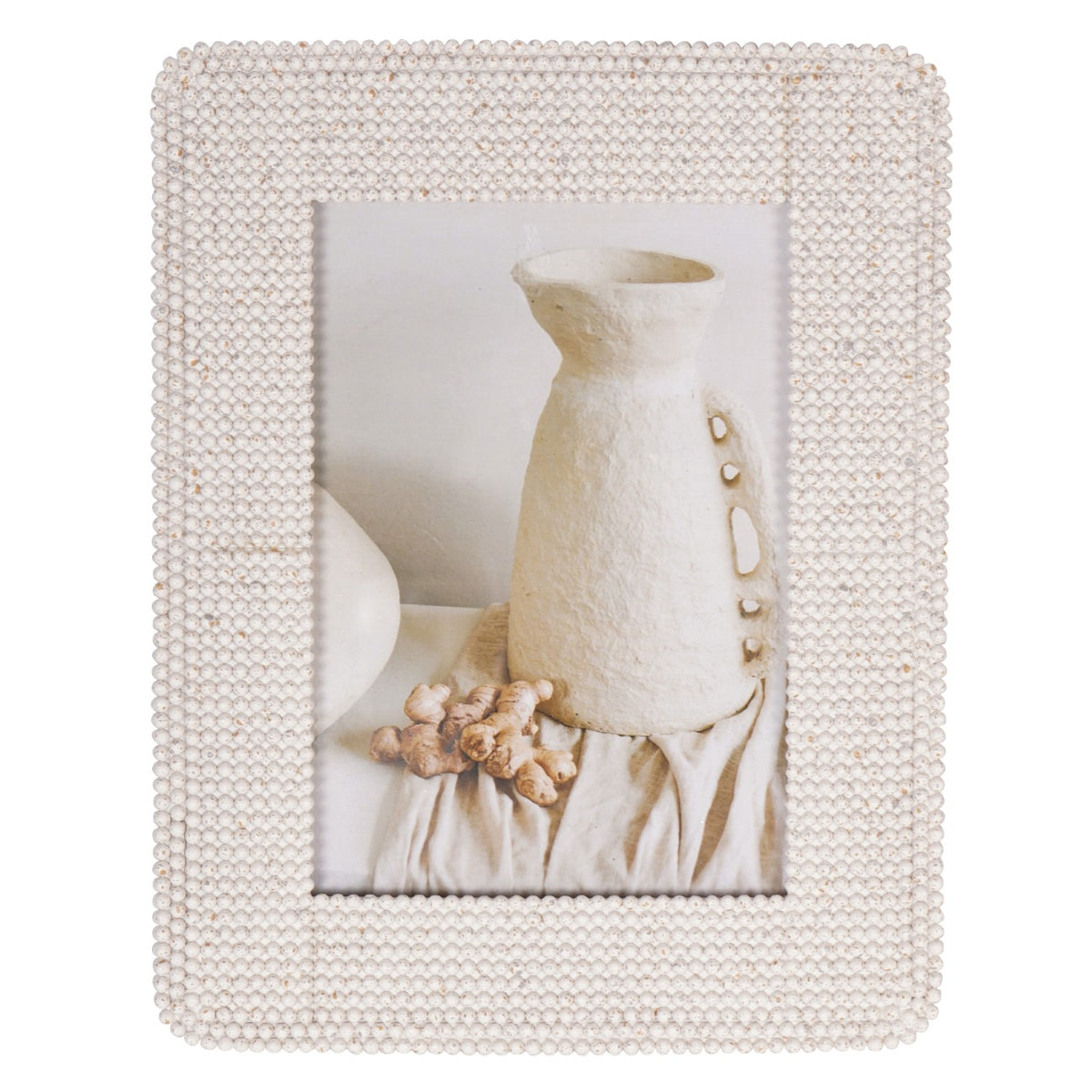 Straight-on view of the cream frame with a broad beaded border surrounding a photograph of pale pottery and draped fabric.