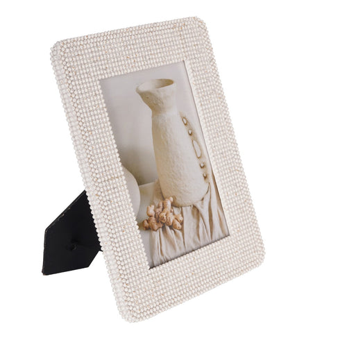 Angled front view of the cream beaded photo frame standing in portrait orientation, with its black easel visible behind.