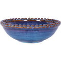 Blue ceramic bowl viewed at an angle, showing its curved body, open interior and brown and blue beaded rim.
