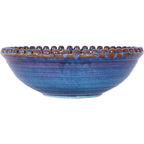 Side view of the blue bowl showing its low curved profile, narrow circular foot and raised beads around the rim.
