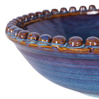 Close-up of the ceramic beads along the bowl's rim, showing glossy brown tops and blue glaze around their bases.