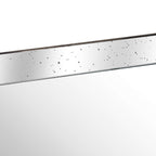 Close-up of the tray's mirrored inner side with scattered dark speckles, a slim distressed rim and the reflective base below.