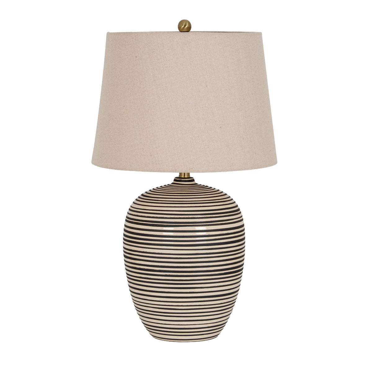 Table lamp on a white background with a rounded black and cream striped body, tapered beige shade, gold-coloured neck and round finial.