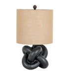 Black Interlock Table Lamp on a white background, with a tan cylindrical shade, dark ball finial and rounded loops forming the base.