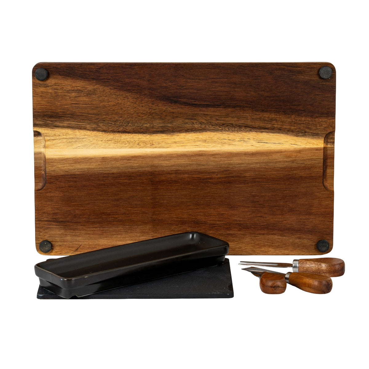 Underside of the brown grained board showing four black corner pads, with the black dish, dark insert and three utensils positioned in front.