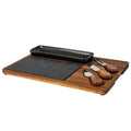Angled view of a brown grained cheese board with a long glossy black dish, dark rectangular insert and three brown-handled utensils in fitted recesses.