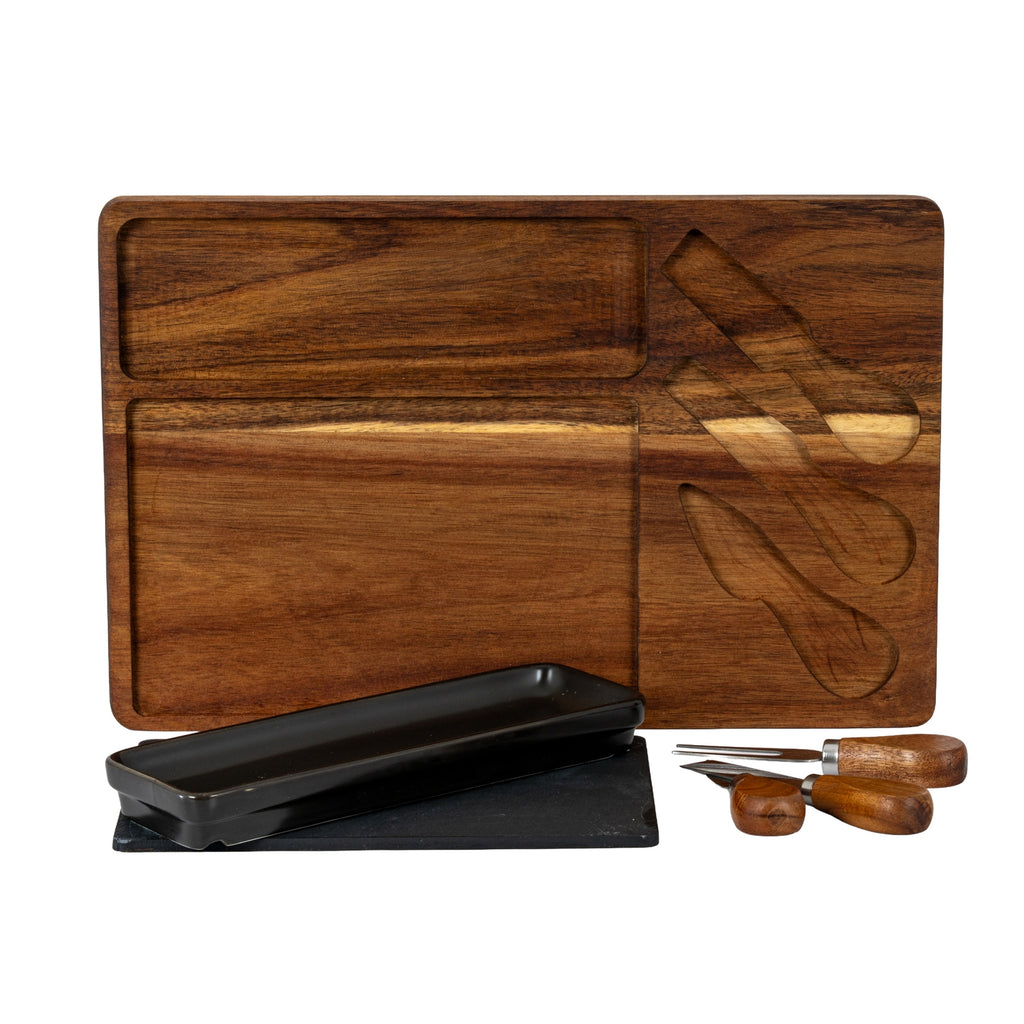 Brown grained board showing its empty rectangular and utensil-shaped recesses, with the black dish, dark insert and three utensils arranged in front.