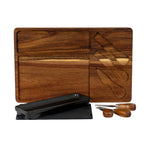 Brown grained board showing its empty rectangular and utensil-shaped recesses, with the black dish, dark insert and three utensils arranged in front.