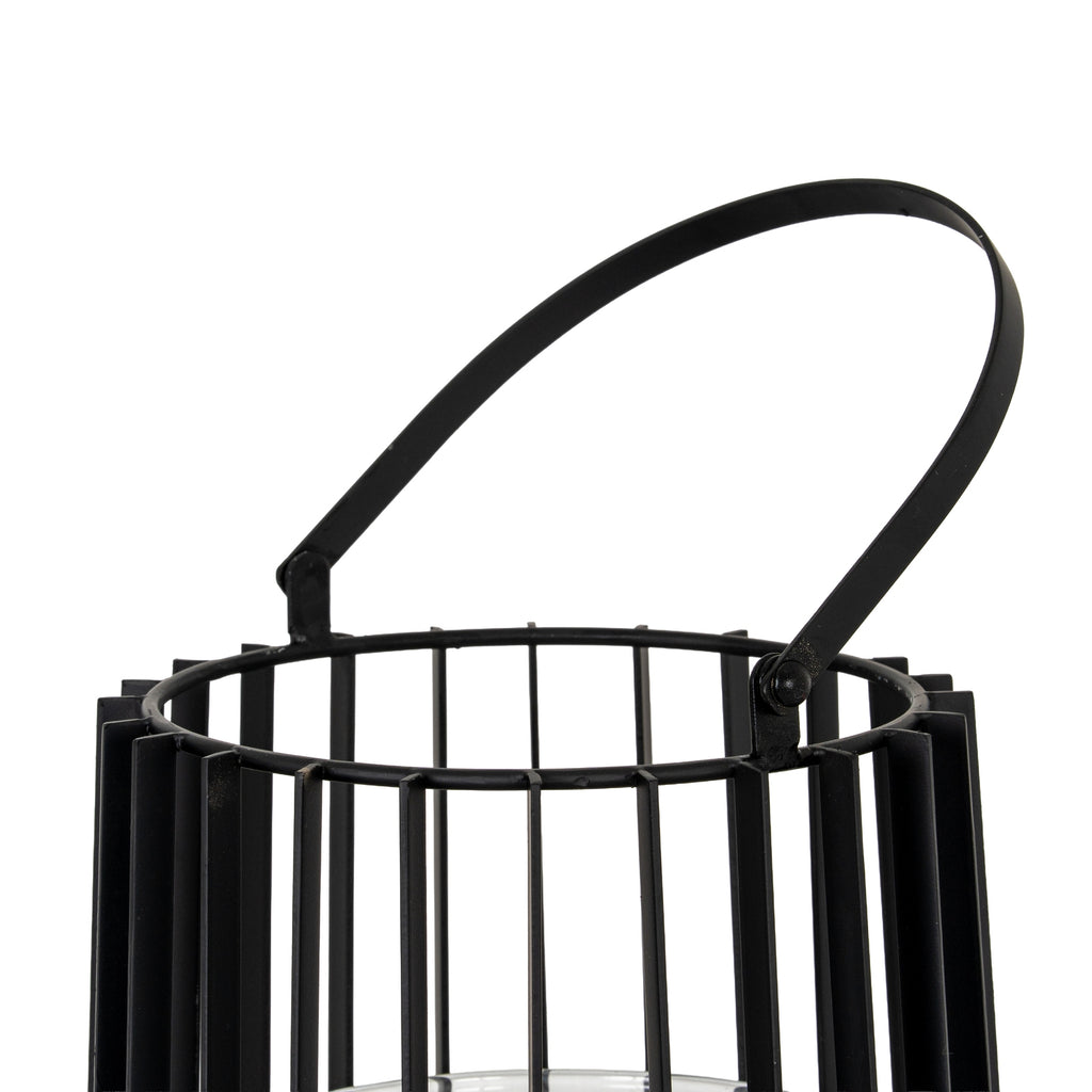 Angled close-up of the black lantern's tilted handle and round side attachment, above the circular rim and vertical frame.