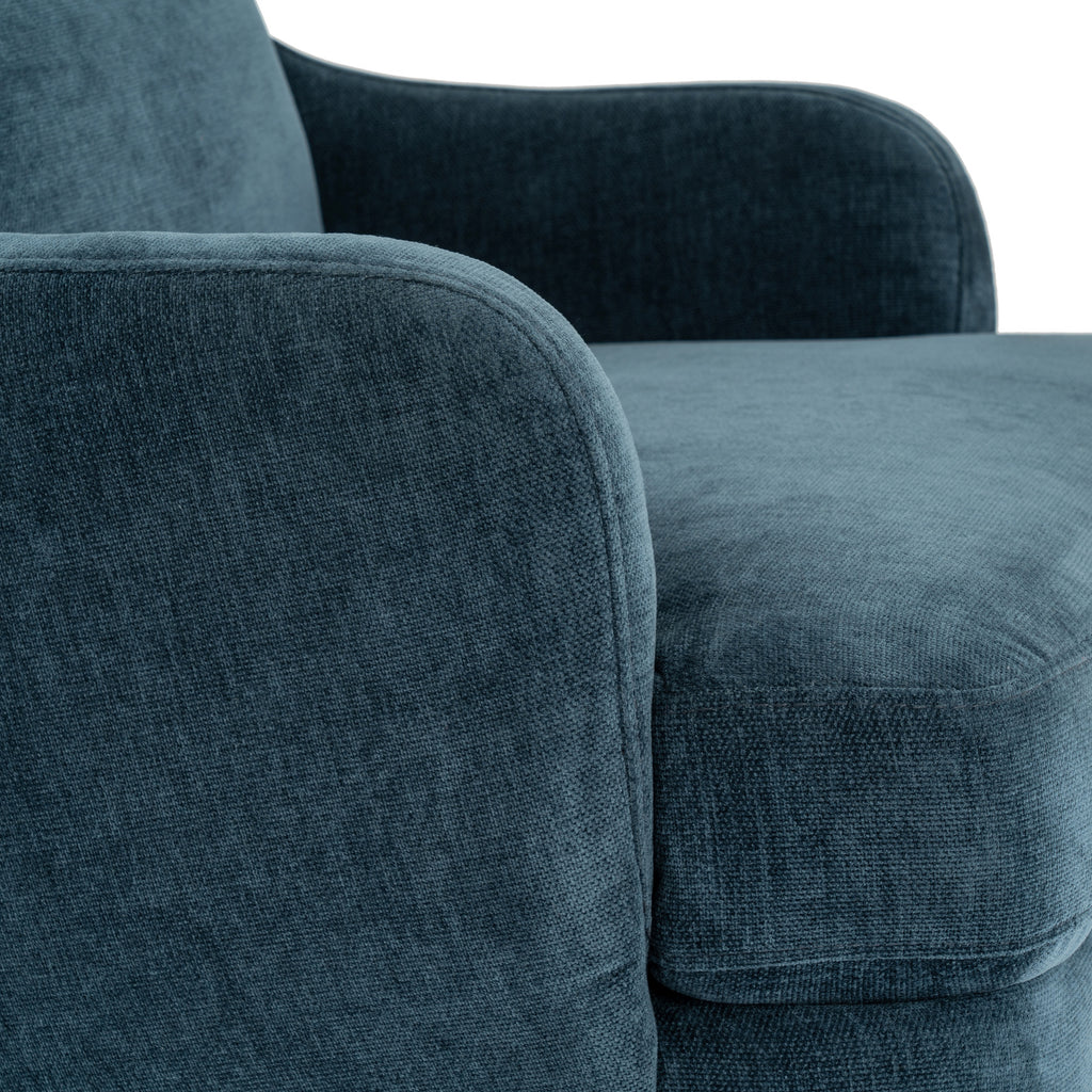 Close-up of the blue upholstery, showing fine surface texture and seams around the curved arm and seat cushion.