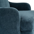 Close-up of the blue upholstery, showing fine surface texture and seams around the curved arm and seat cushion.