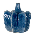 Blue ceramic vase with a narrow open neck and broad upright fins with wavy edges, showing pale flecking and glossy highlights against a white background.