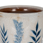 Close-up of the planter's blue leaf pattern, fine crackle lines and beige-brown surface marks beneath the rim, with the brown interior visible.