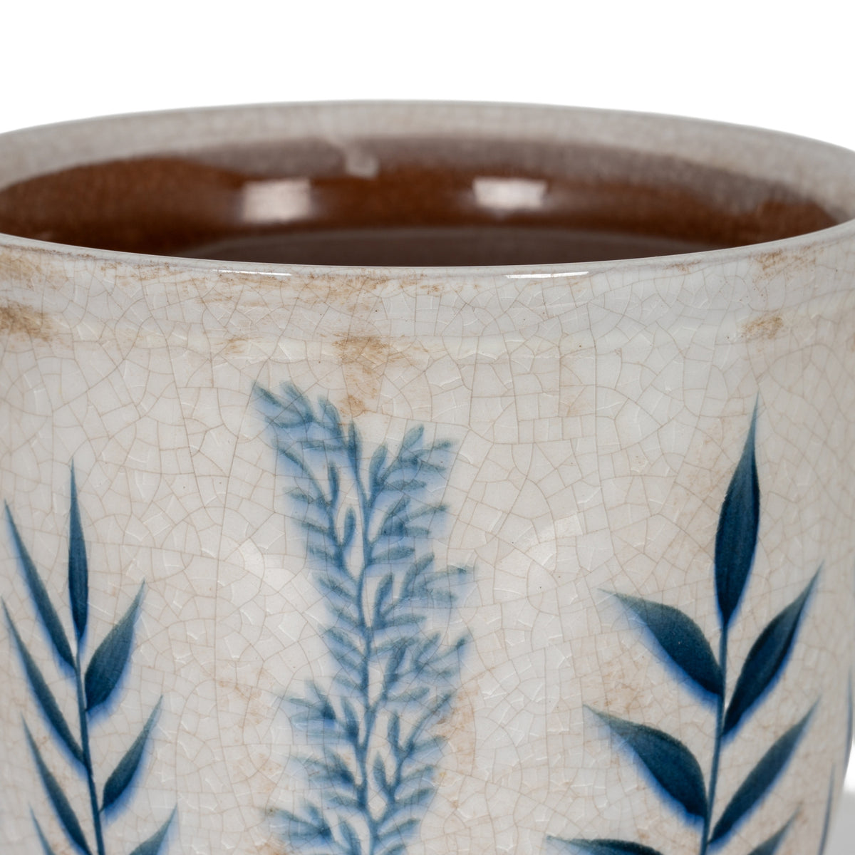 Close-up of the planter's blue leaf pattern, fine crackle lines and beige-brown surface marks beneath the rim, with the brown interior visible.