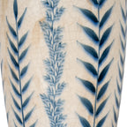 Detail of dark blue pointed leaves beside a fine misty-blue botanical stem, with crackle lines across the warm off-white surface.