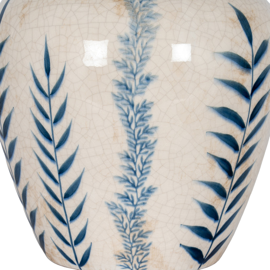 Detail of deep blue leaves flanking a misty blue stem on the vase's glossy off-white crackle surface.