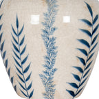 Detail of deep blue leaves flanking a misty blue stem on the vase's glossy off-white crackle surface.