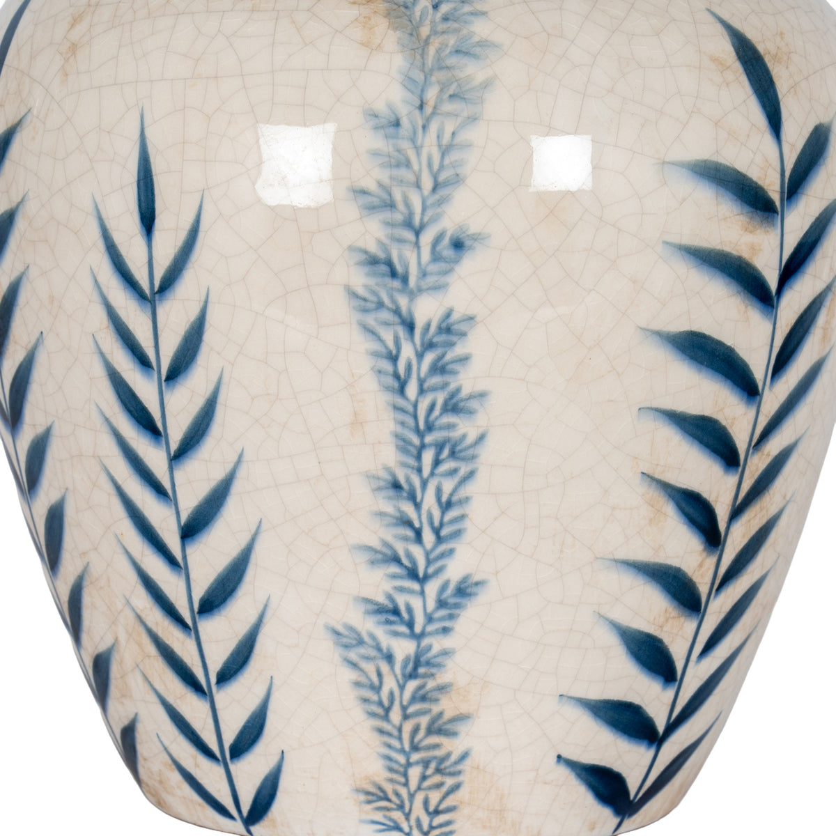 Detail of deep blue leaves flanking a misty blue stem on the vase's glossy off-white crackle surface.