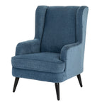 Three-quarter front view of a blue wing armchair with tall rolled wings, curved arms, a piped seat cushion and slim black legs.