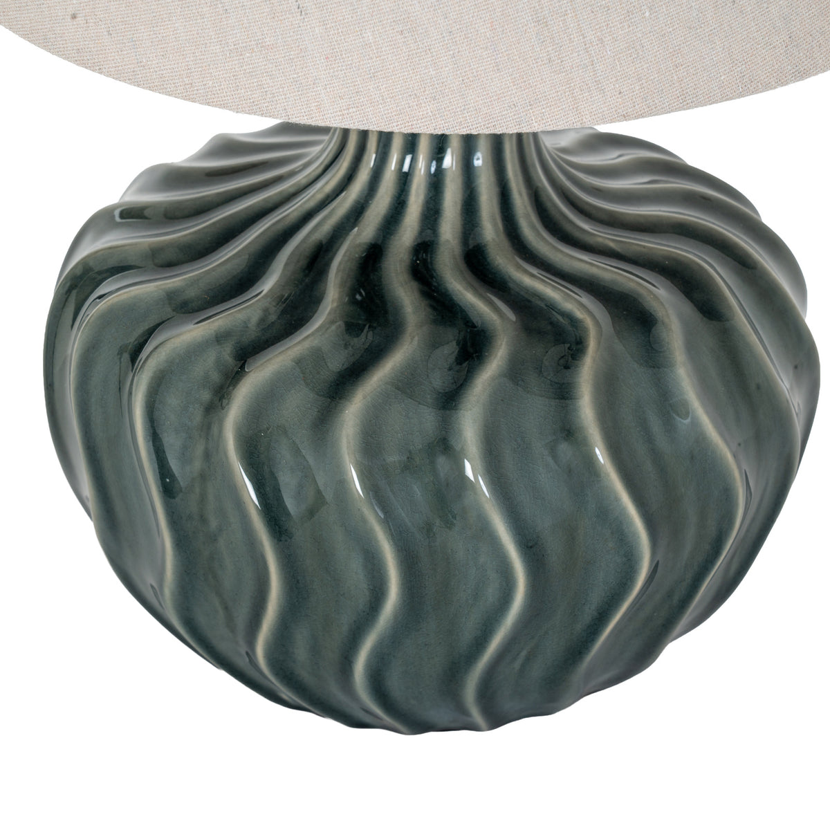 Close-up of the lamp's glossy blue-green curves and lighter flute edges beneath the woven pale shade.