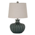 Bluegreen Waveflute Table Lamp with a rounded dark blue-green body, flowing vertical flutes and a pale tapered shade against white.