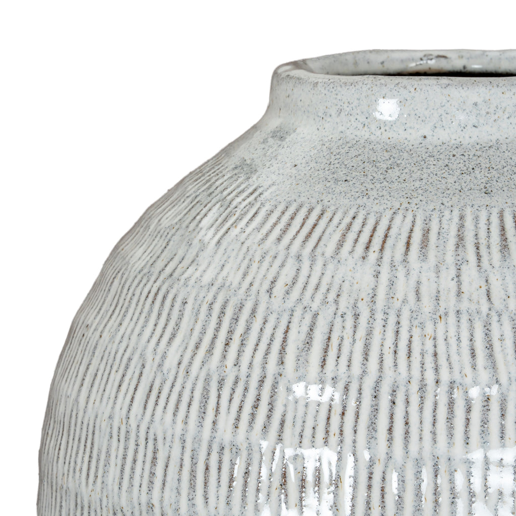 Close-up across the vase shoulder, showing darker incised lines beneath the pale glossy glaze and fine scattered speckles.