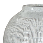 Close-up across the vase shoulder, showing darker incised lines beneath the pale glossy glaze and fine scattered speckles.