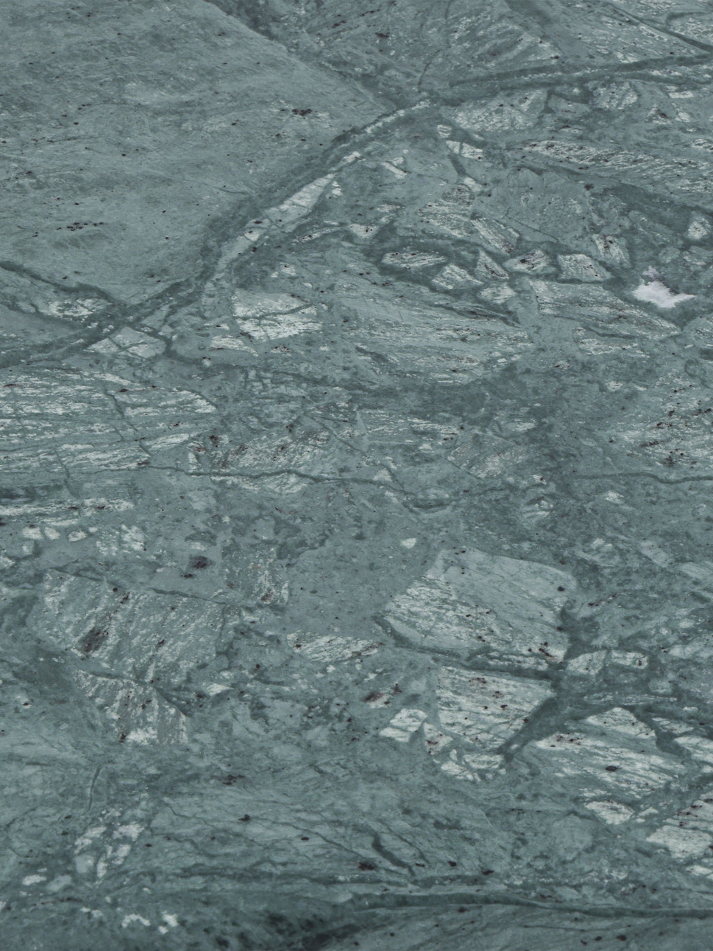Close-up of the green marble surface with pale patches, fine dark lines and irregular natural markings.