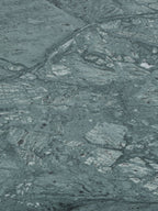 Close-up of the green marble surface with pale patches, fine dark lines and irregular natural markings.