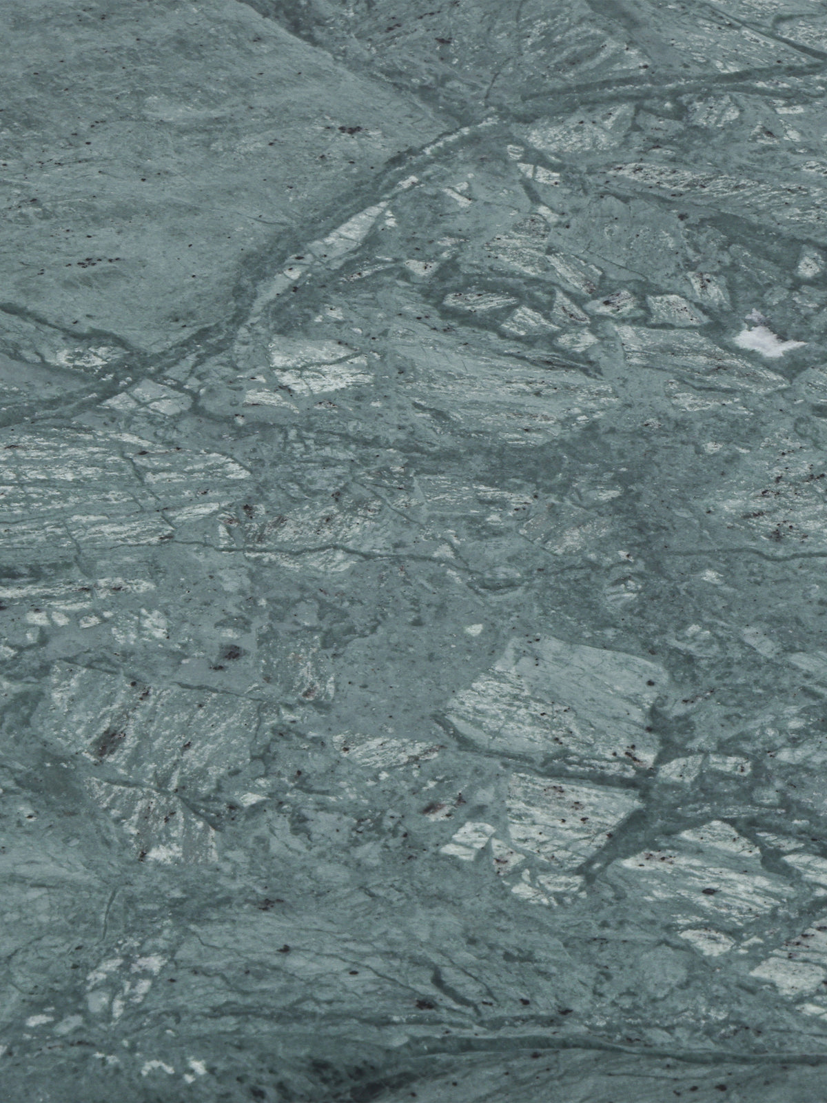Close-up of the green marble surface with pale patches, fine dark lines and irregular natural markings.