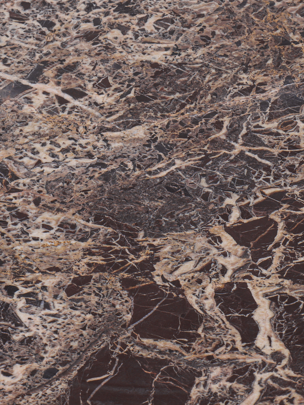 Close-up of the marble surface with dense cream, beige and grey veining through dark red stone.