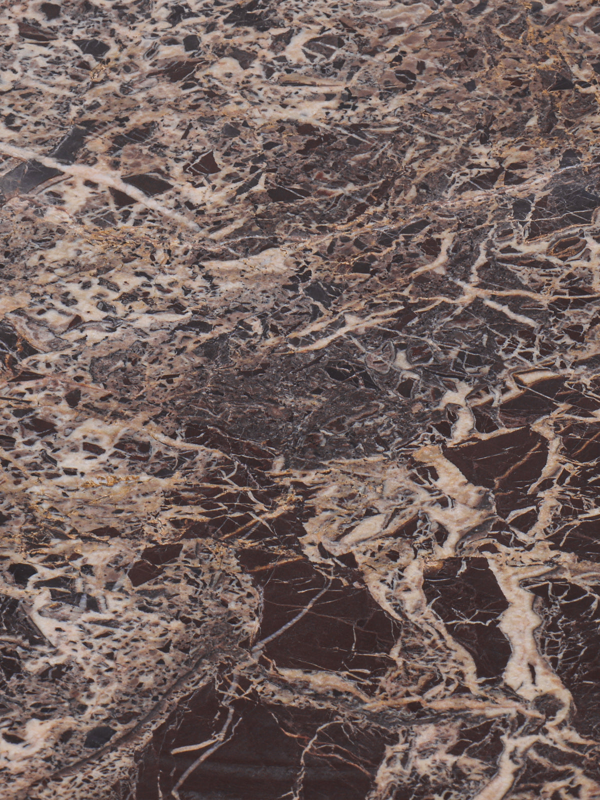 Close-up of the marble surface with dense cream, beige and grey veining through dark red stone.