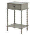 Pale grey side table shown at an angle, with a framed drawer, dark round knob, four bobbin legs and a rectangular lower shelf.
