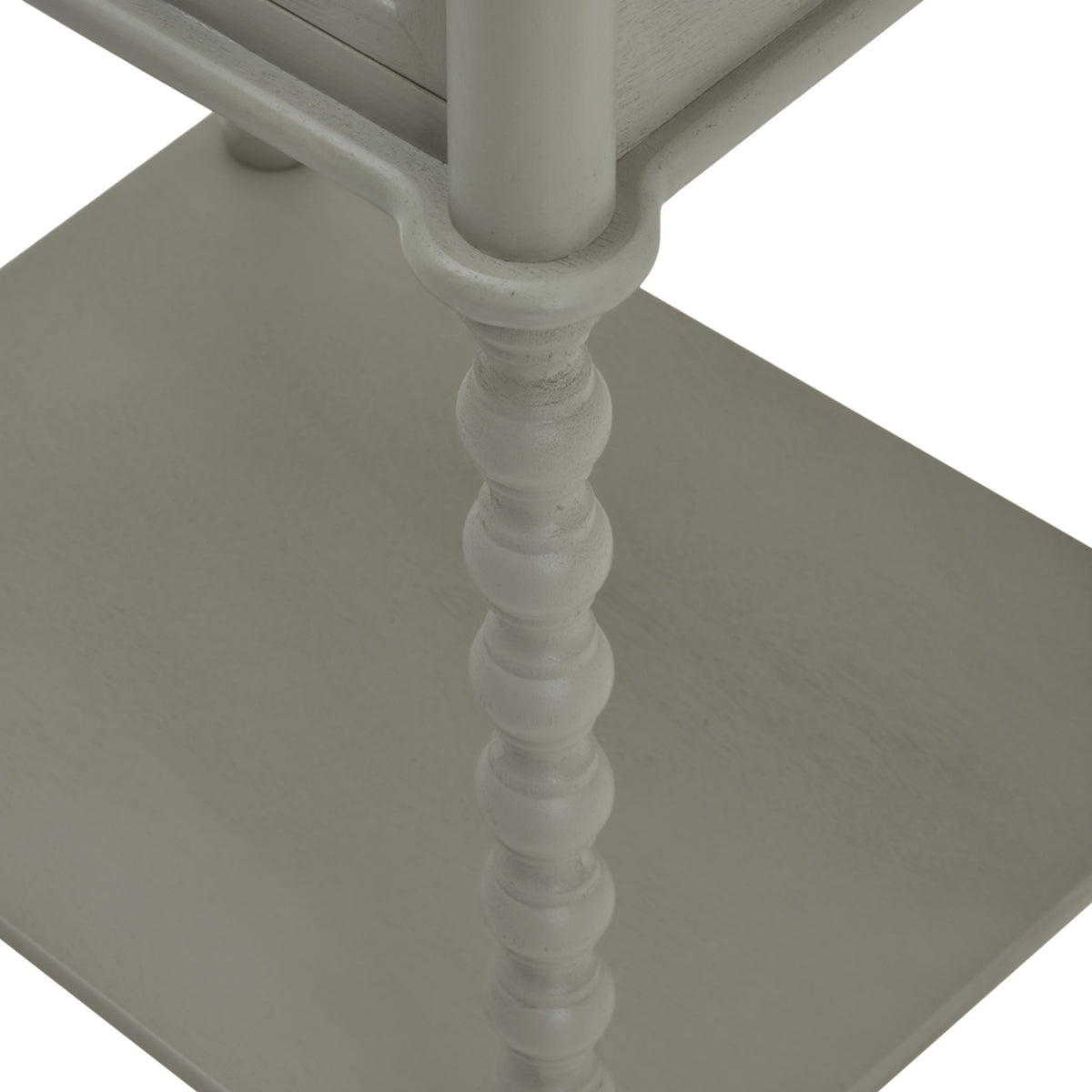Close view looking down the table's curved bobbin leg towards the pale grey lower shelf.