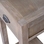 Angled close-up of the tabletop corner, drawer front and side panel with light grain highlights across the pale-brown surface.