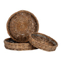 Three differently sized round brown woven trays, with one standing upright behind a flat tray and a smaller tray tilted at the front, showing bound rims and concentric woven bases.
